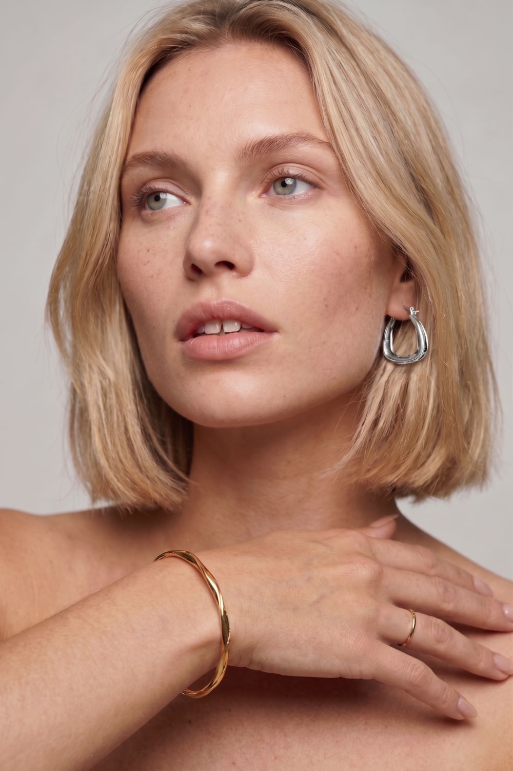 Woman with blonde hair and jewelry on a neutral background