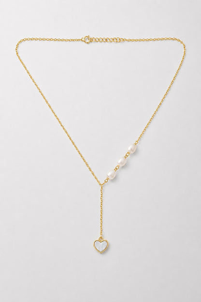 A delicate gold Y-necklace featuring a row of white pearls on one side and a small gold heart pendant with a white inlay on the other, displayed on a light gray background.