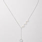 A delicate silver Y-necklace featuring a central row of white pearls and a dangling silver heart charm, displayed on a clean light gray background.