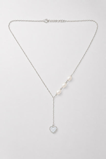 A delicate silver Y-necklace featuring a central row of white pearls and a dangling silver heart charm, displayed on a clean light gray background.