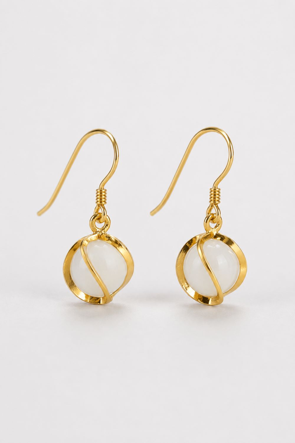 A pair of gold-tone dangle earrings with circular white stone bezels, shown on a clean white background.