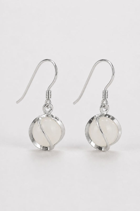 A pair of silver-toned dangle earrings with oval milky white stone drops, shown on a clean light gray background.