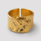 A textured gold open cuff ring with a hammered, organic surface finish, shown on a neutral light gray background. The brand name 'ORGANSK' is subtly engraved inside the band.