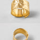 A wide, textured gold ring shown from two angles on a light gray background, with one view displaying the open clasp detail and the other showing the polished inner band.