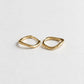 A pair of small gold huggie hoop earrings with a textured, organic wavy outline, displayed on a clean white background.