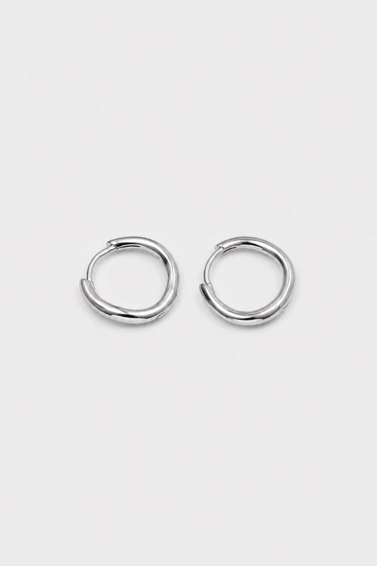 A pair of polished silver-toned metal hoop earrings with a unique twisted, organic loop design, displayed on a clean, light gray background.