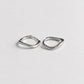 A pair of small, abstract silver hoop earrings with a textured, organic wavy outline, displayed on a clean, light gray background.