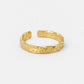 A textured gold open cuff bracelet with a hammered, organic surface finish, displayed on a clean white background.