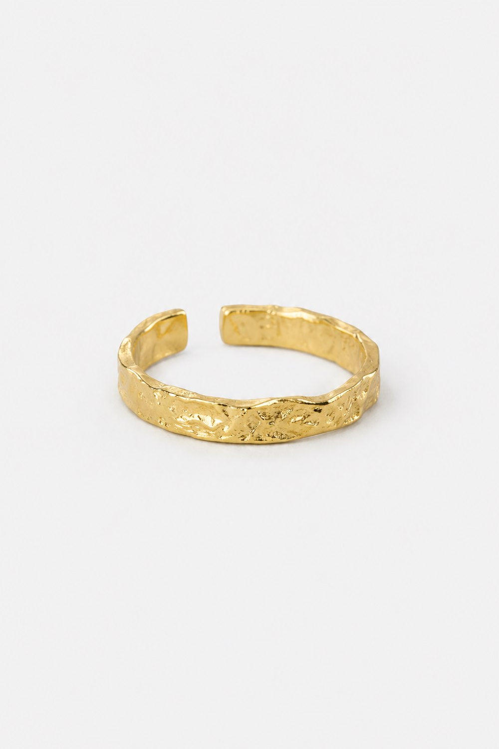 A textured gold open cuff bracelet with a hammered, organic surface finish, displayed on a clean white background.