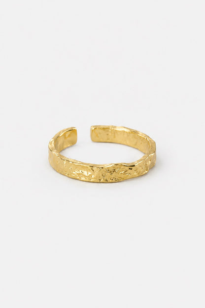 A textured gold open cuff bracelet with a hammered, organic surface finish, displayed on a clean white background.