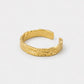 A textured gold open cuff ring with a hammered, organic surface finish, displayed on a clean white background.