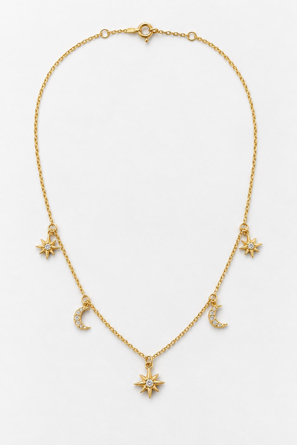A delicate gold chain necklace featuring celestial charms, including a central sunburst pendant, two crescent moons, and two starbursts, displayed on a clean white background.