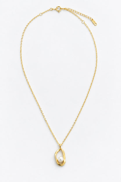 A delicate gold chain necklace featuring a unique pendant with a textured, organic gold frame enclosing a single white pearl, displayed on a clean white background.