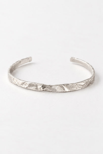 A textured silver cuff bracelet with an organic, hammered surface, displayed on a clean white background.
