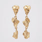 A pair of gold dangle earrings with organic, textured shell-like drops, shown against a light gray background.