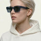 Person wearing dark sunglasses and a white hoodie against a light background