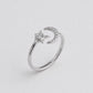 A silver-toned ring featuring a crescent moon and star design, accented with small clear stones, set against a plain light gray background.