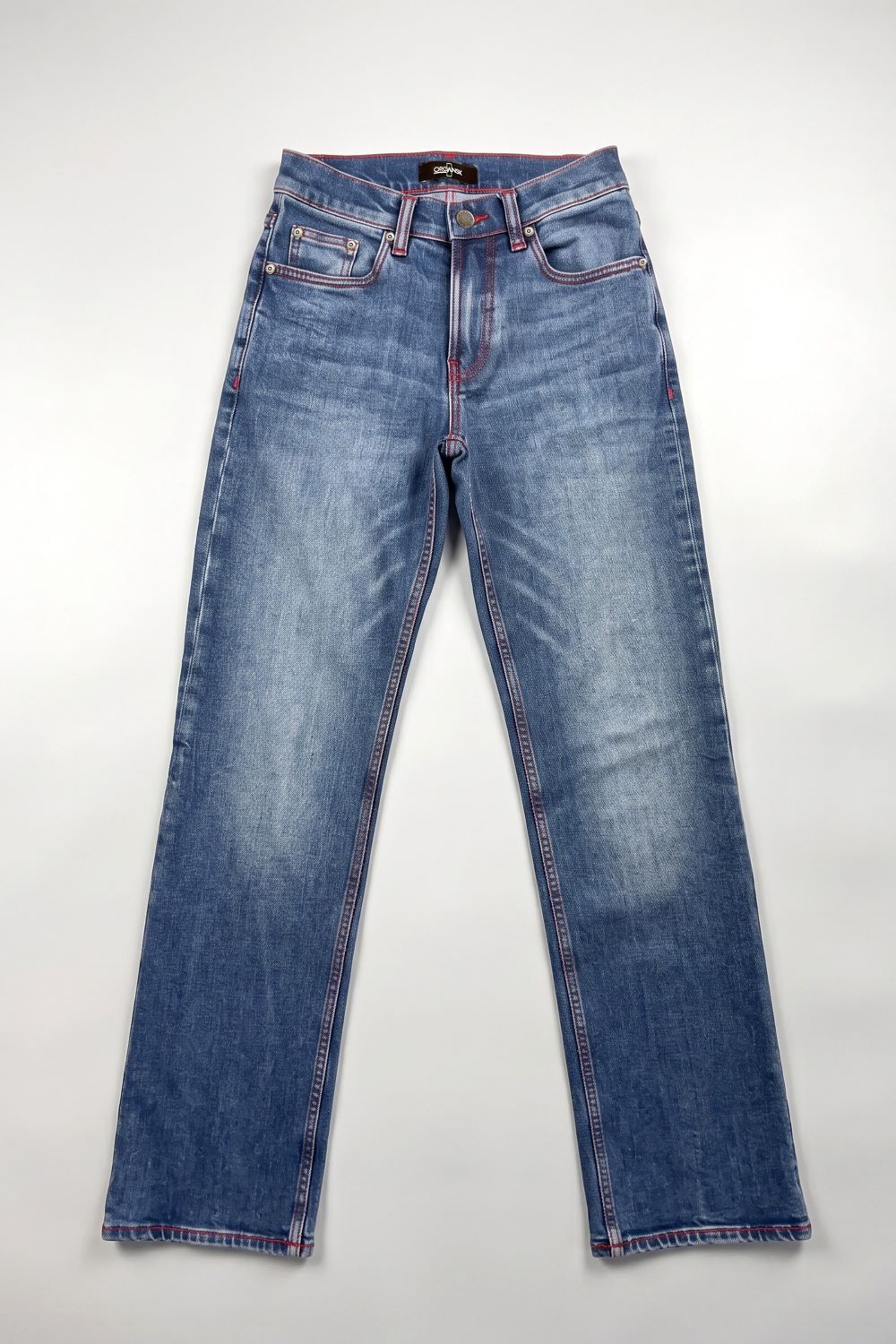 A pair of medium-wash blue denim jeans with contrast red stitching, laid flat against a light gray background.