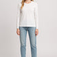 Woman wearing a white long-sleeve top and light blue jeans on a white background