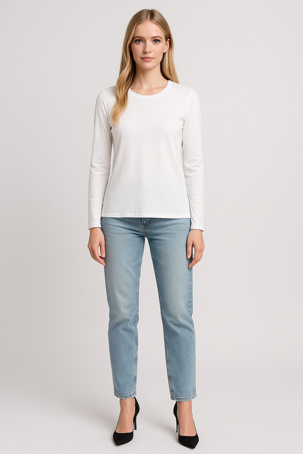 Woman wearing a white long-sleeve top and light blue jeans on a white background