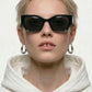 Person wearing black sunglasses and a white hoodie on a plain background